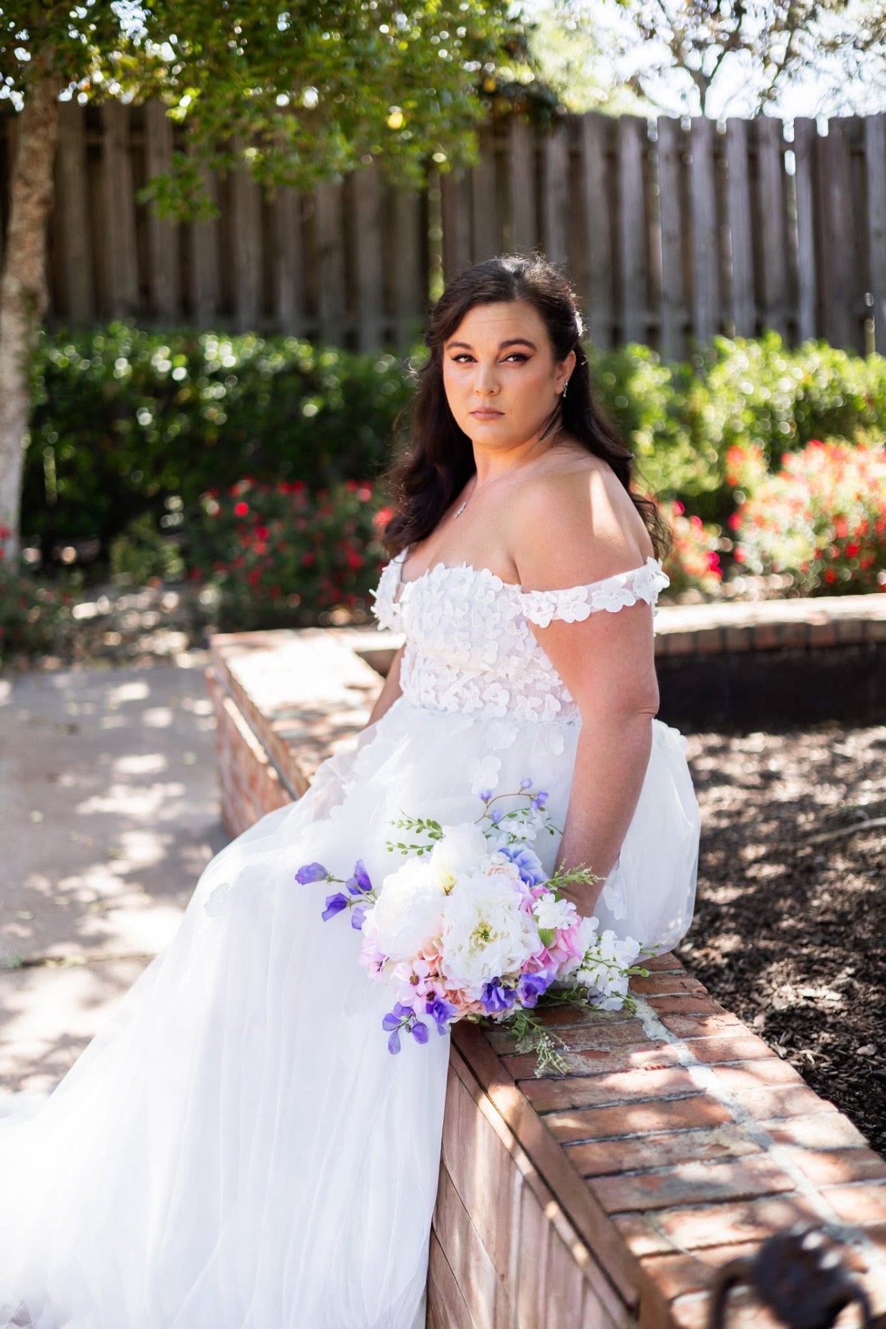 Real bride — warm smoky glam and loose waves on a garden bench